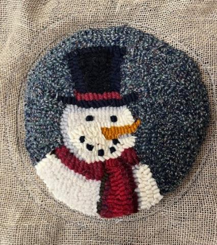 Colorful rug-hooked snowman medallion on a beige background