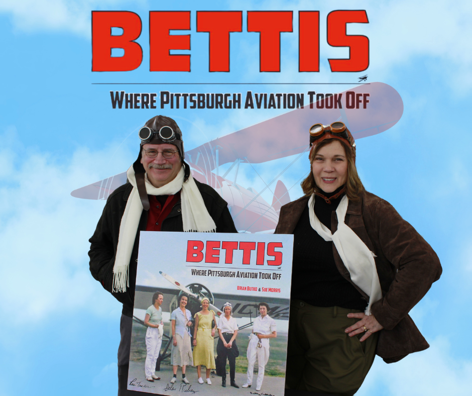 Authors in front of sky holding book on Bettis Airport