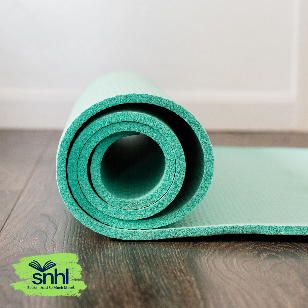 Partially unrolled teal yoga mat on wood floor with white wall background